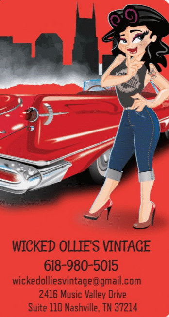 Cartoon woman with tattoos poses in front of a red vintage car; city skyline in background. Wicked Ollie's Vintage contact info displayed below.